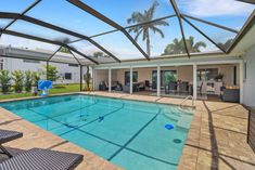 an indoor swimming pool in the middle of a backyard with chairs and tables around it