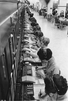 several women sitting at desks working on electronic equipment