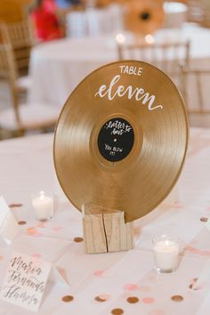 a table topped with a golden record next to candles and napkins on top of a white table cloth