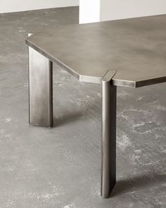 a table that is sitting on the floor in front of a white wall and concrete floor