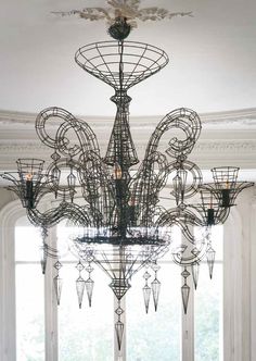 a large chandelier hanging from the ceiling in a room with white walls and windows