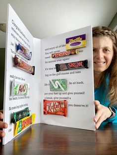 a woman holding up an open book with candy bars on the front and side of it