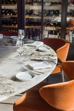 the table is set with wine glasses, plates and utensils