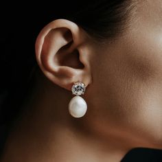 a woman wearing a pair of earrings with pearls on the ear and a diamond in the middle