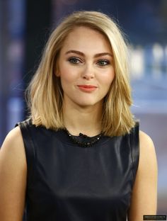 a close up of a person wearing a black dress and looking at the camera with a serious look on her face