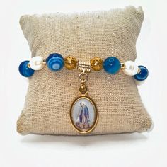 Beautiful adjustable bracelet made of blue agates and river pearls with a significant and beautiful Italian Miraculous Medal that will be perfect and highly appreciated for a confirmation gift, for a mother or grandmother or any woman of faith. The Miraculous Medal was designed according to the instructions of the Blessed Virgin Mary herself!! The Virgin said... "Have a medal minted according to this model, the people who wear it will receive great gratitude. Graces will be abundant for those wh Blue Beaded Bracelet With Pearl Charm For Gift, Blue Beaded Bracelet With Pearl Charm As Gift, Blue Beaded Bracelet With Pearl Charm, Adjustable Blue Beaded Bracelet With Pearl Charm, Adjustable Blue Pearl Bracelet With Natural Stones, Spiritual Pearl Bracelet As Gift, Spiritual Pearl Bracelet 8mm Beads Gift, Spiritual Pearl Bracelet With 8mm Beads As Gift, Blue Agate Stretch Bracelet Gift