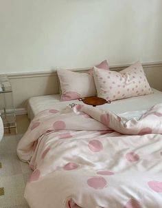 a bed with pink polka dot sheets and pillows