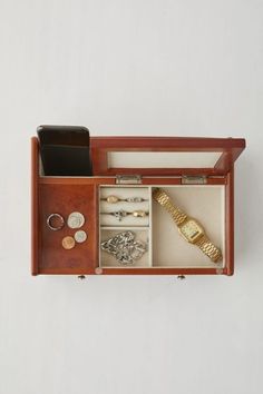 an open wooden box with various items inside on a white surface, including a watch and bracelet