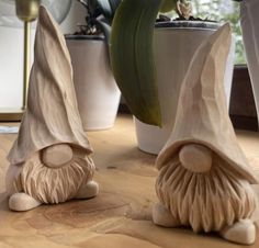 two clay sculptures sitting on top of a wooden table next to a potted plant