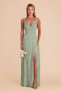 a woman in a long green dress with a slit down the side and flowers on it