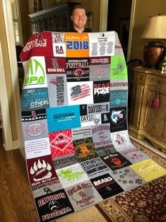 a man is standing in front of a quilt made out of t - shirts and other items