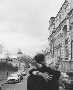 black and white photograph of two people hugging each other on the side of a road