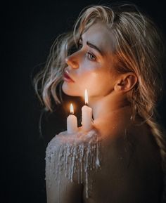 a woman holding two candles in front of her face with icing on the body