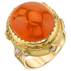 For a look that is regal and refined, look no further than our 18k yellow gold signature band set with an impressive 24.39 carat Mandarin spessartite garnet cabochon. This spectacular gemstone is a statement of true luxury and exquisite taste. The color of a perfect Mandarin orange (hence its name), this translucent and extremely vibrant gem has been masterfully set in a custom-made, intricately engraved 18k yellow gold bezel. Huge and bold, this is a statement ring that is neither masculine nor Yellow Gold Cocktail Ring, Raw Stone Jewelry, Spessartite Garnet, Hessonite Garnet, Gold Cocktail Ring, Gold Cocktail, 18k Yellow Gold Ring, Mandarin Orange, Domed Ring