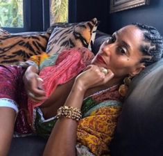 a woman sitting on top of a couch next to a tiger print pillow and pillows