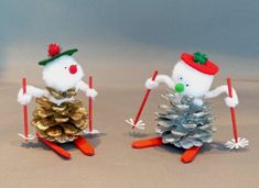 two knitted snowmen are standing next to each other with pine cones on their feet