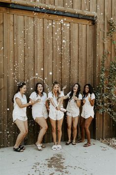 a group of young women standing next to each other in front of a wooden fence