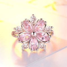 a pink flower shaped ring sitting on top of a table