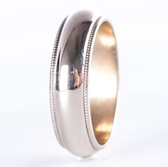 a close up of a wedding ring on a white background with the reflection of a person in it