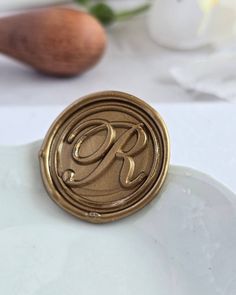 a close up of a wax seal on a white plate with flowers in the background