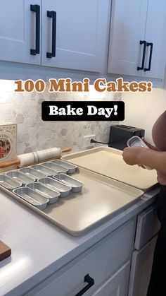 a woman standing in front of a kitchen counter with baking pans on it and the words, 100 mini cakes bake day