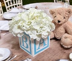 a teddy bear sitting next to a vase with flowers in it on top of a table