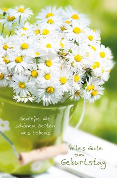 a green bucket filled with white daisies on top of a table