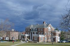 a large brick building sitting on top of a lush green field under a cloudy sky