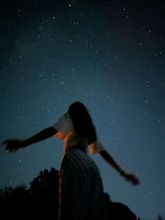 a person standing in the dark with their arms spread out to the stars above them