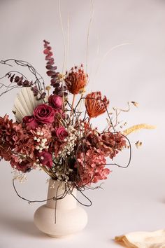 a vase filled with lots of flowers on top of a white table next to a pair of scissors