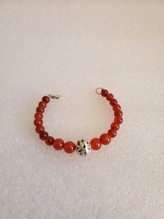 "This handmade Genuine Carnelian Beaded Bracelet was made on Silver Wire with round Genuine Carnelian Ball Beads. The bracelet is closed off using a 925-lobster clasp and jump ring. At the center is medium size Silver Ornate Metal Ball that is the focal point. This bracelet was handmade by Dulcinea for a small wrist and all items used are new. This bracelet would be a great gift and will arrive in a gift box with FREE SHIPPING. Measure: 6 5/8\" L Material: Genuine Carnelian in Round Shape, 925 L Red Carnelian Beaded Bracelets With Round Beads, Red Carnelian Beaded Bracelet With Round Beads, Red Carnelian Round Beads Bracelet, Adjustable Carnelian Bracelet As A Gift, Adjustable Carnelian Bracelet Perfect For Gifts, Carnelian Round Beads Bracelet For Gift, Amber Carnelian Beaded Bracelets - Gift, Amber Carnelian Beaded Bracelet Gift, Red Carnelian Beaded Bracelets