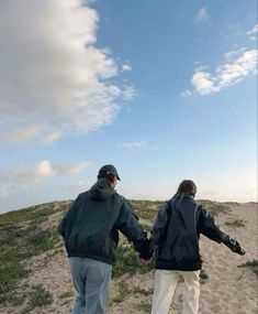 two people holding hands while walking on the beach