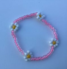 a pink and white beaded bracelet with flowers on the end, sitting on a blue surface