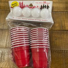 red plastic cups are sitting in a package on the wooden floor, ready to be used