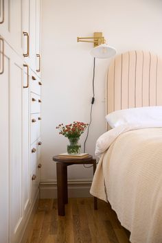 a bedroom with a bed, nightstand and flower pot on the end table in front of it