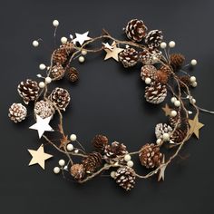 a wreath made out of pine cones and white berries with gold stars on the side