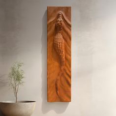 a plant is sitting in front of a wall sculpture that has a seahorse on it