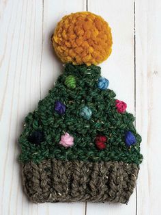 a crocheted christmas tree ornament on top of a white wooden surface