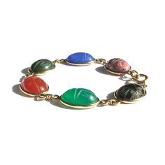 Our customers love colorful jewelry that celebrates change and signifies self transformation.  Scarabs are what makes this vintage gemstone bracelet a personal symbol for the self or a loved one about to embark upon big changes and a new life. The sacred scarab, a dung beetle, was the image of self-creation in Ancient Egypt. In hieroglyphs the scarab meaning is "to be transformed" and was a symbol of new life.  Six stunning carved colorful gemstone scarabs of tigers eye, green chalcedony, carnelian, bloodstone, blue chalcedony black and pink rhodonite are linked between shiny gold filled links in this 12k yellow gold filled bracelet from the 1960s made by Van Dell.  Scarab bracelet measures 7.5 inches long by .5 inches wide.  The loop end is marked Van Dell and 1/20 12K GF. The vintage gem Scarab Meaning, Self Transformation, Dung Beetle, Personal Symbol, Eye Green, Scarab Bracelet, Pink Rhodonite, Green Chalcedony, Vintage Bracelet