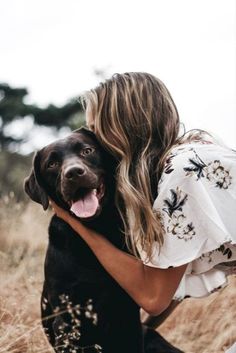 a woman is hugging her dog in the field