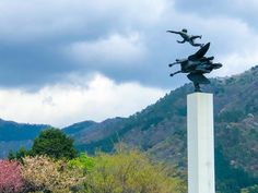 a statue in the middle of a park with mountains in the background