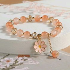 Introducing Our Stunning Peach Pink Color Flower Charm Glass Beaded Bracelet A Beautiful Accessory That Will Add A Touch Of Feminine Elegance To Any Outfit! This Bracelet Is Crafted With Care And Features Delicate Glass Beads In A Gorgeous Peach Pink Color That Exudes Softness And Sophistication. With Its Adjustable Length, This Bracelet Can Comfortably Fit Most Wrist Sizes. The Stretchy Band Ensures A Secure And Flexible Fit, Allowing You To Easily Slide It On And Off Without Any Hassle. The Fl Elegant Adjustable Crystal Bracelet For Spring, Elegant Flower Crystal Bracelet For Spring, Elegant Flower Shaped Crystal Bracelet For Spring, Elegant Spring Bracelet With Colorful Beads, Spring Crystal Bracelet With Round Beads, Elegant Flower Beaded Bracelets For Spring, Elegant Spring Flower Beaded Bracelets, Elegant Beaded Flower Bracelets For Spring, Spring Crystal Bracelet With Round Beaded Details