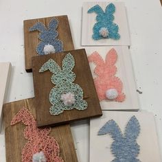 four wooden plaques with crocheted bunny ears and pom poms on them