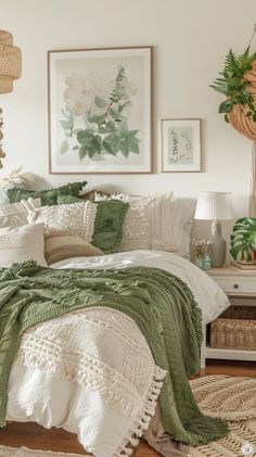 a bed with green and white comforters in a bedroom next to a table filled with plants