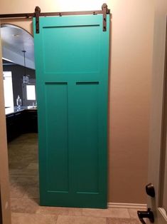 a green door is opened to reveal a room with tile flooring and beige walls