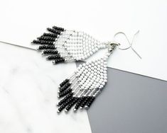 the black and white beaded earrings are hanging from silver hooks