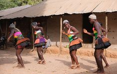 three women are dancing in front of a hut