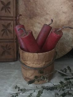 a wooden bucket filled with red candles on top of a table