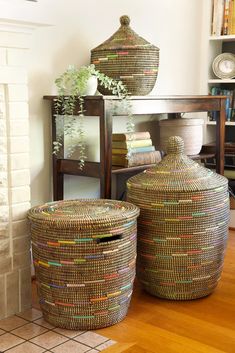 two large baskets sitting on top of a wooden floor next to a shelf filled with books