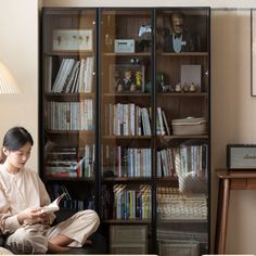 a woman sitting on a couch in front of a book shelf filled with lots of books